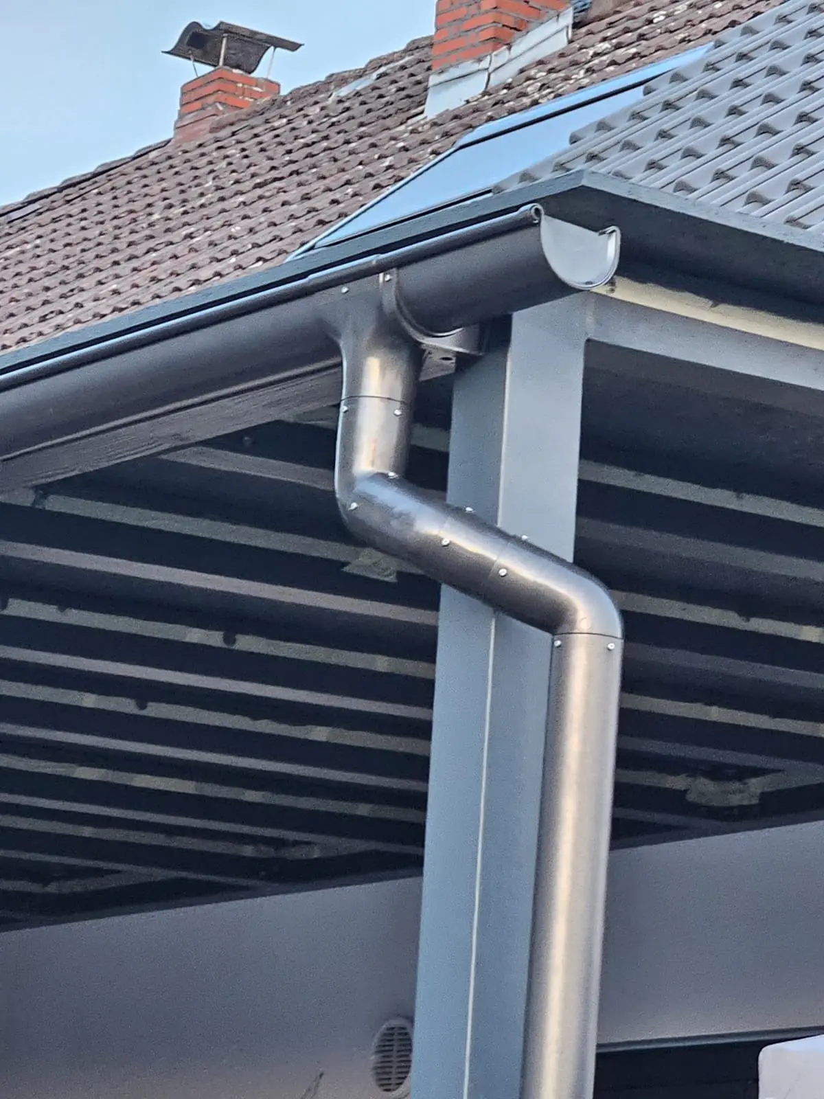 Neu montierte Dachrinne und Fallrohr aus Metall